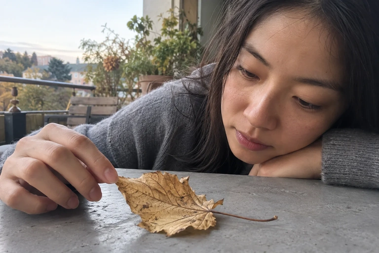 Une femme observe une feuille posée sur une table de balcon