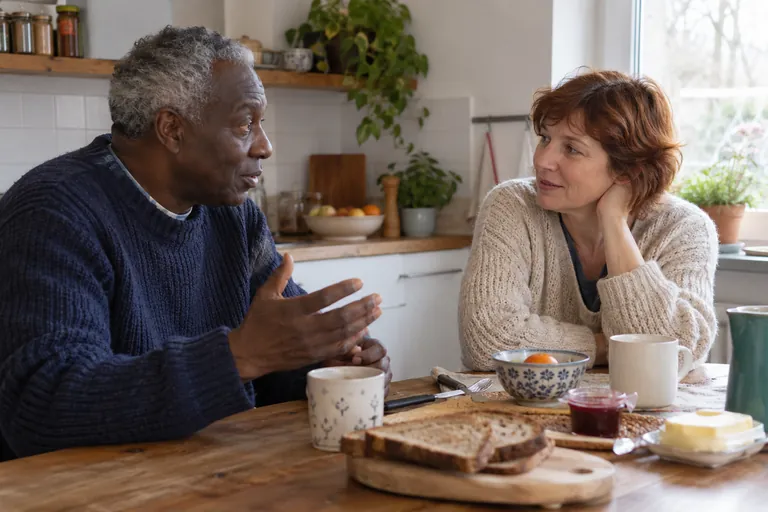Deux adultes discutent à une table de cuisine