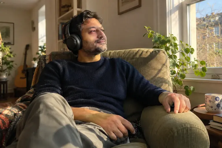 Un homme écoute un audio au casque, assis confortablement les yeux ouverts