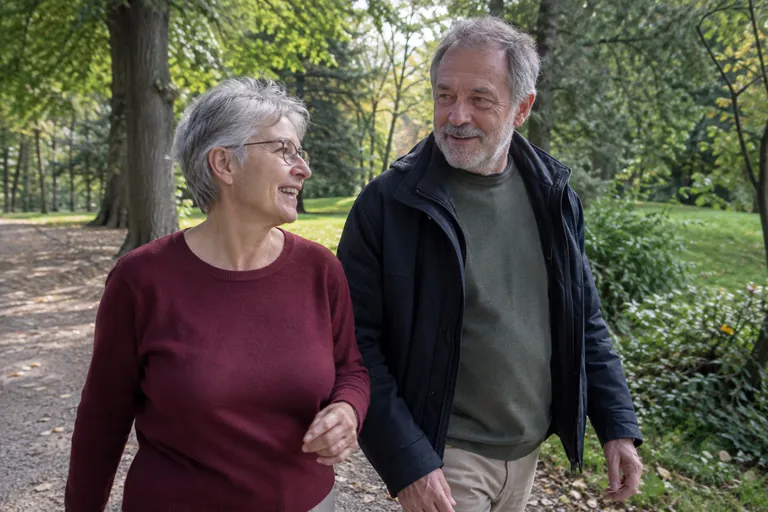 Une femme et un homme marchent ensemble dans un parc.
