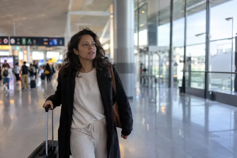 Une voyageuse marche dans un terminal d’aéroport avec une petite valise