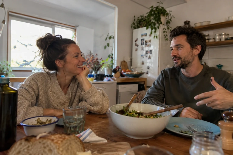 Deux adultes discutent autour d’un repas simple dans une cuisine