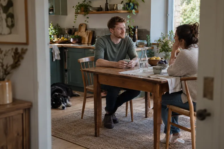 Deux adultes discutent autour d’une table de cuisine