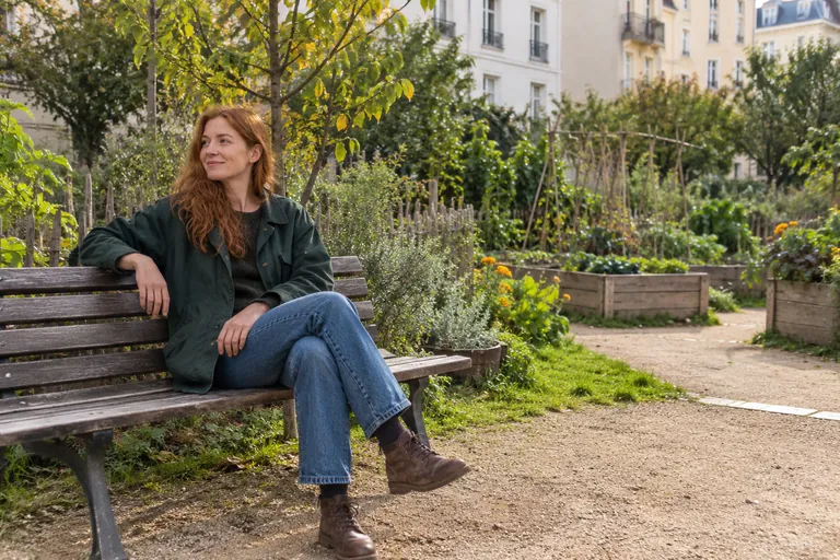 Une femme se repose sur un banc dans un jardin urbain