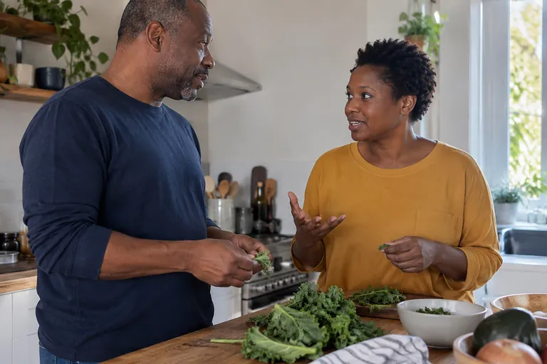 Une femme et un homme échangent en préparant des légumes dans une cuisine.