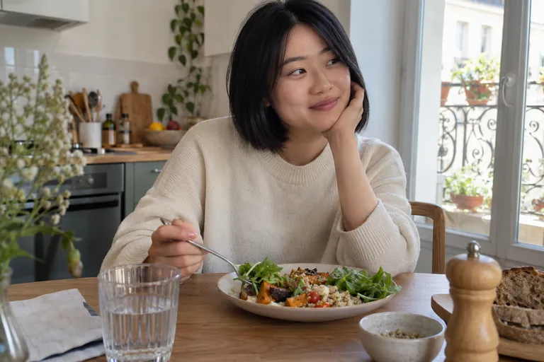 Une femme est assise devant son repas dans une cuisine