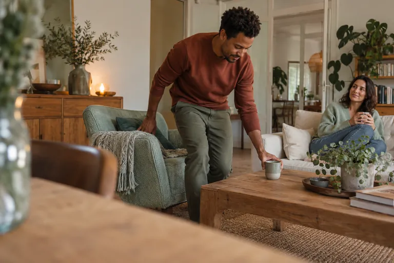 Un homme pose une tasse sur une table basse