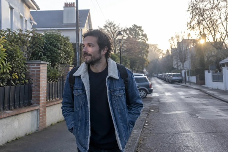 Un homme marche dans une rue résidentielle au matin