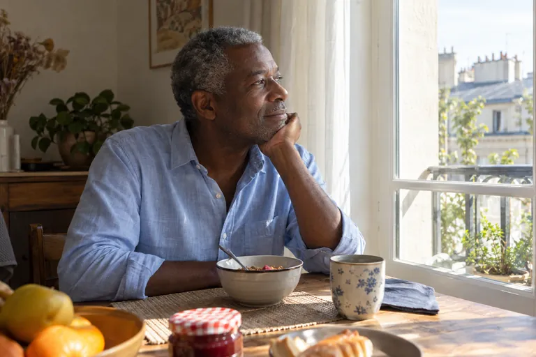Un homme regarde la fenêtre devant son petit-déjeuner