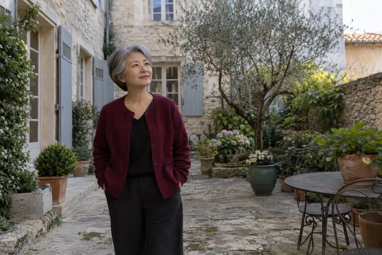 Une femme aux cheveux gris fait une pause dans une cour