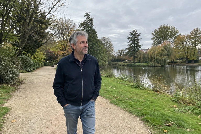 Un homme marche tranquillement dans un parc sous un ciel couvert