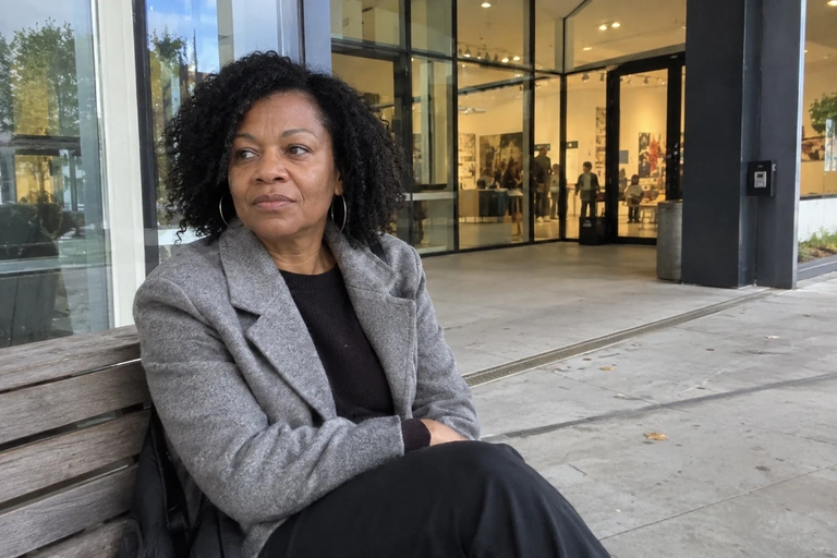 Une femme est assise sur un banc devant une entrée