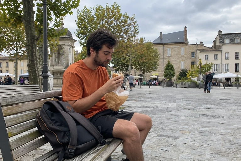 Un homme mange sur un banc d’une place piétonne