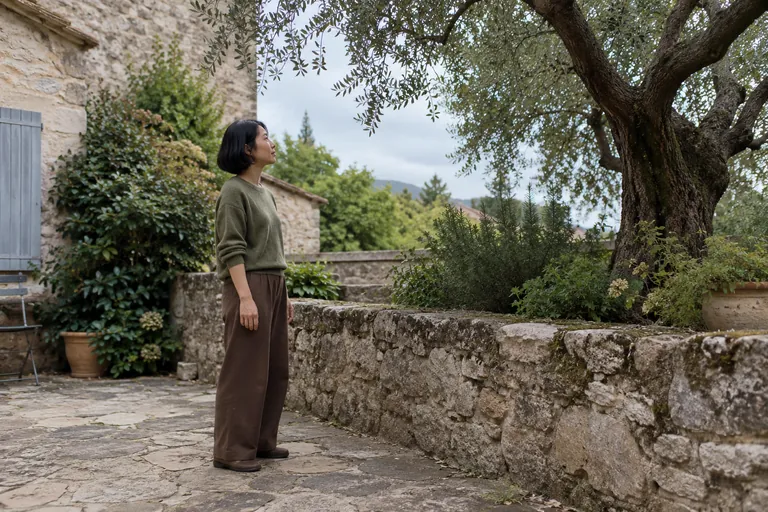 Une femme observe un arbre dans une cour pavée.