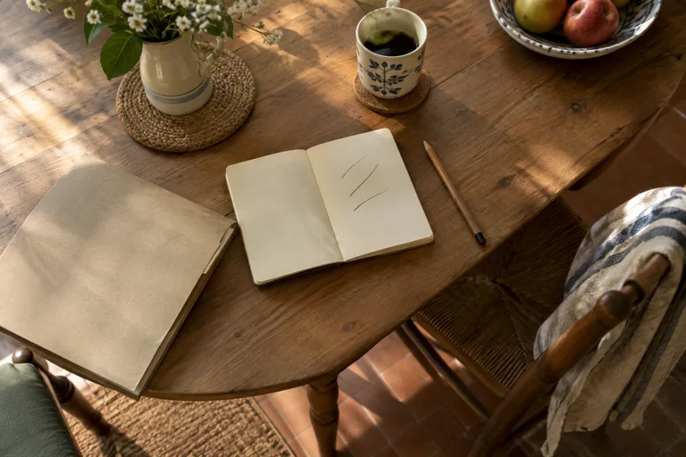 Un carnet, un crayon, une chemise en papier et une tasse sur une table