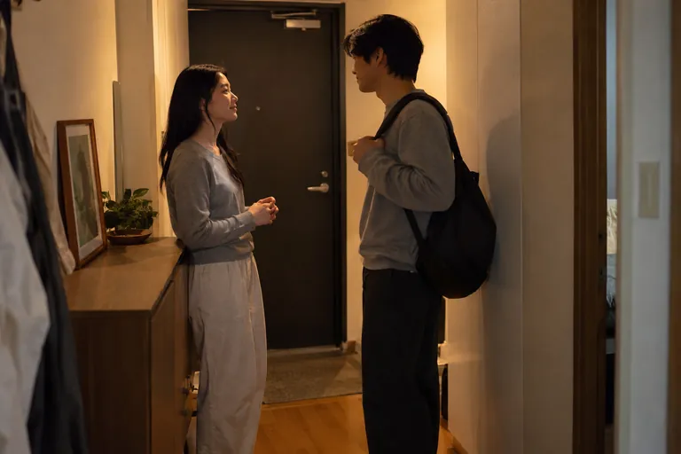 Une femme et un homme portant un sac discutent dans une entrée.