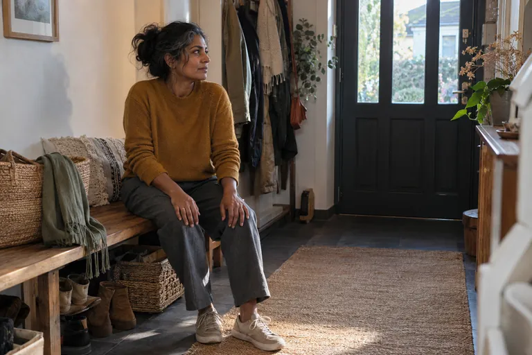 Une femme assise sur un banc pose les mains sur ses cuisses.