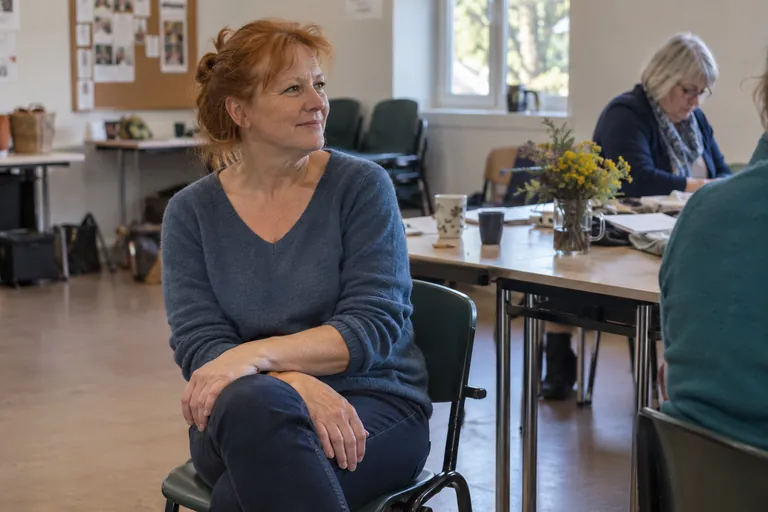 Une femme est assise sur une chaise dans une salle commune.