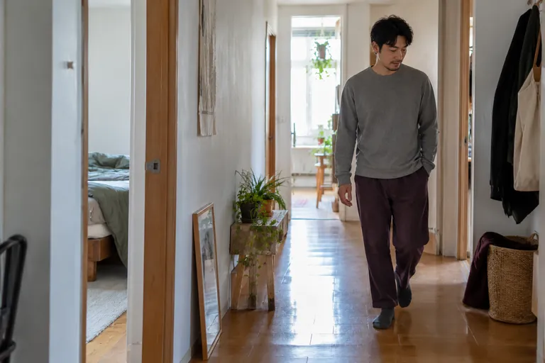 Un homme marche dans un couloir de son logement.