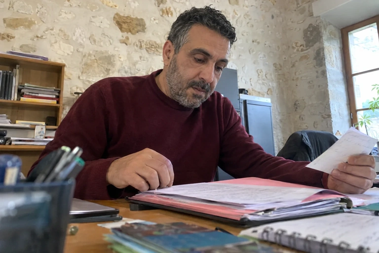 Un homme reprend un dossier dans un bureau associatif