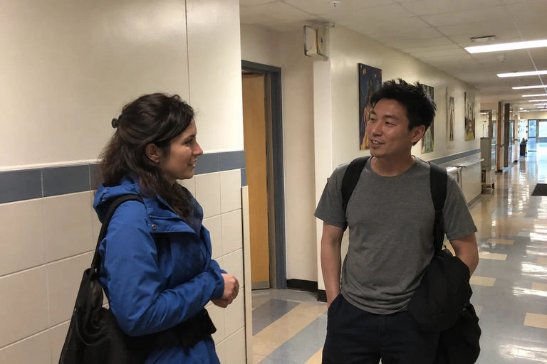 Deux personnes échangent brièvement dans un couloir