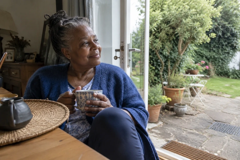Une femme assise près d’une porte de jardin ouverte fait une pause en journée