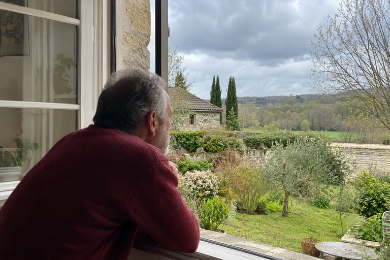 Un homme regarde un jardin depuis une fenêtre ouverte
