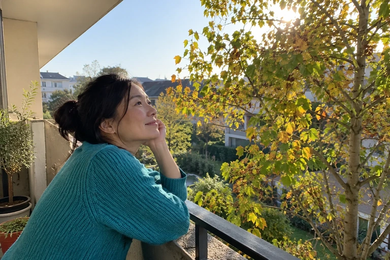 Une femme observe les feuilles d’un arbre depuis un balcon