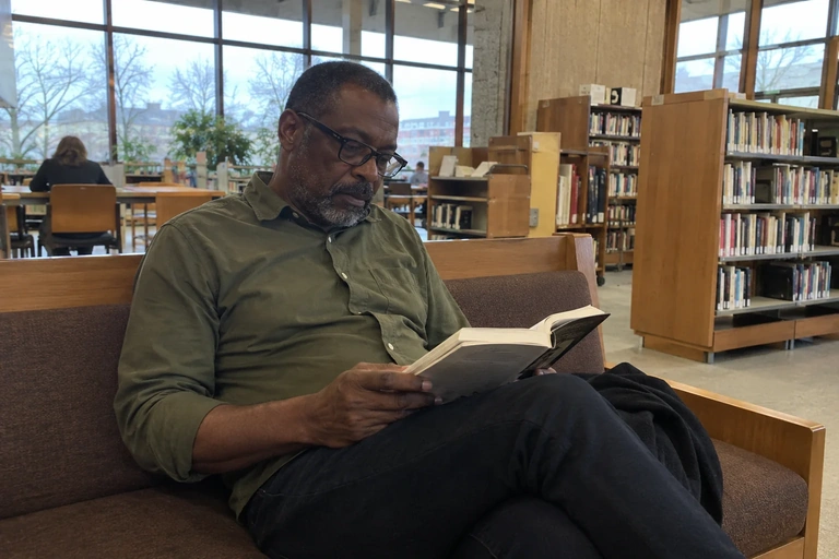 Un homme lit un livre dans une médiathèque