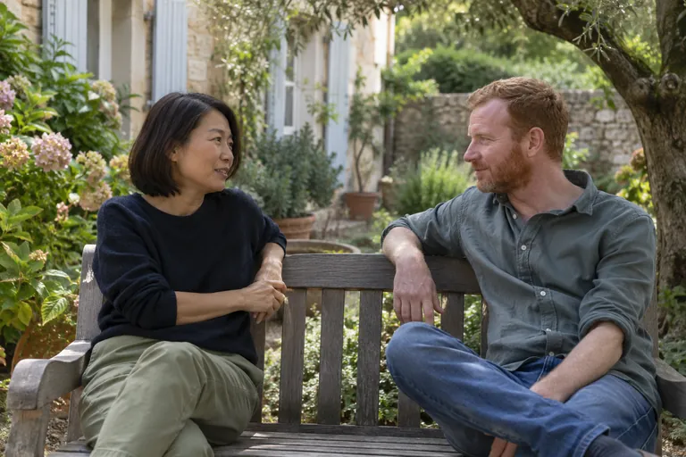 Deux adultes discutent sur un banc de jardin