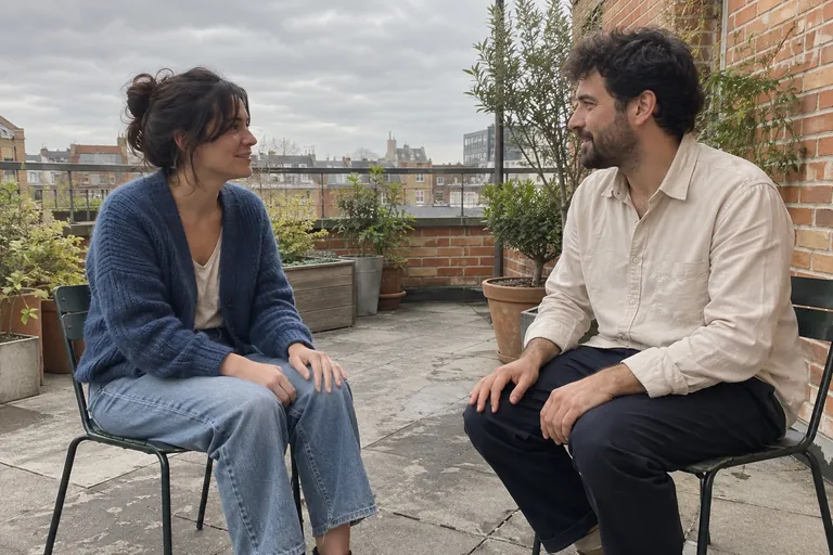 Deux adultes discutent assis face à face sur une terrasse.