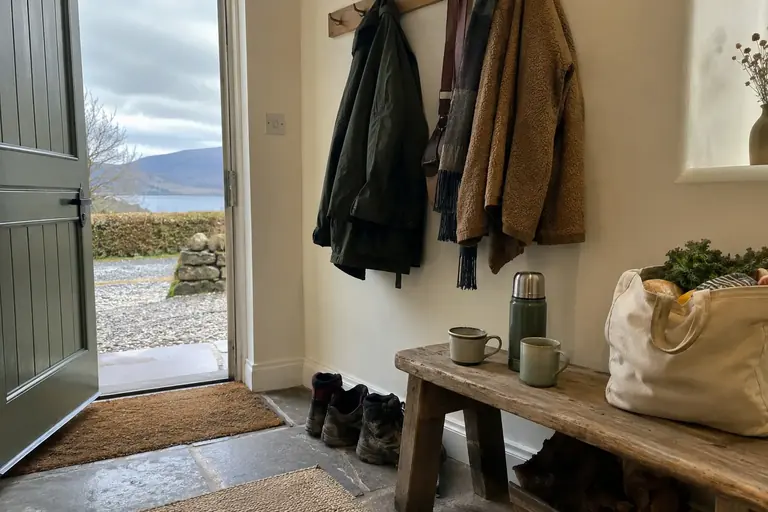 Deux manteaux, deux tasses et un petit sac de courses dans une entrée de maison