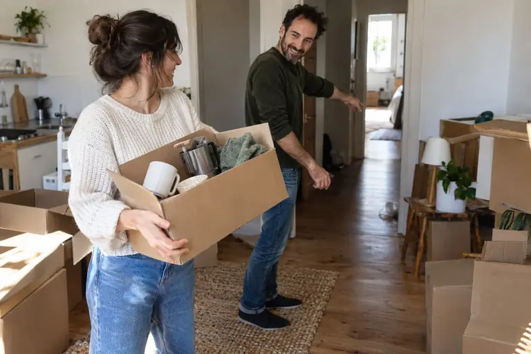 Deux adultes organisent des cartons en gardant un passage libre dans un appartement