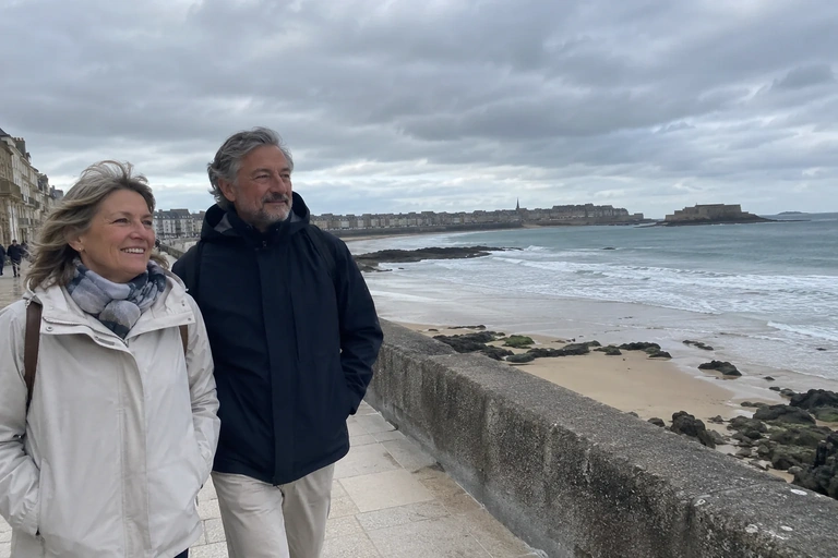 Deux adultes marchent sur une promenade de bord de mer sous un ciel couvert