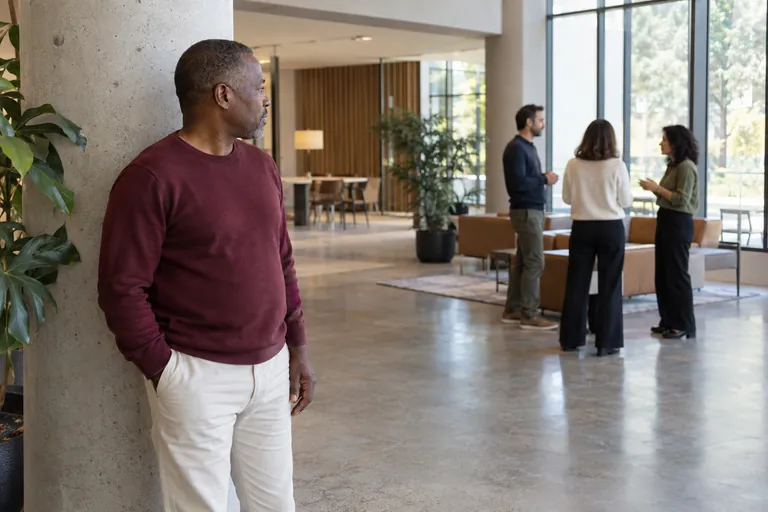 Un homme se tient à l’écart de trois personnes qui discutent dans un hall.