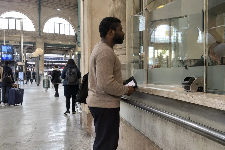 Un homme attend à un guichet avec une pochette de documents