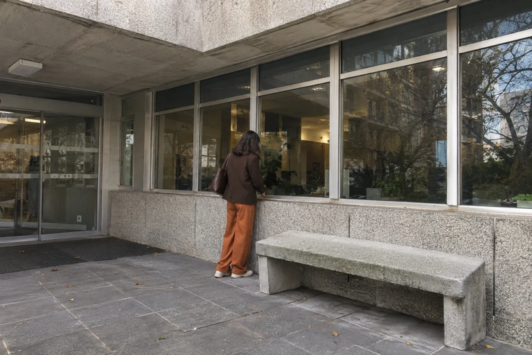 Une personne attend près d’un banc dans un bâtiment administratif