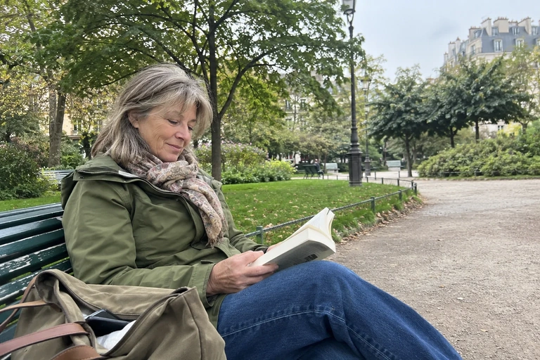 Une femme lit dans un parc, son téléphone rangé dans un sac