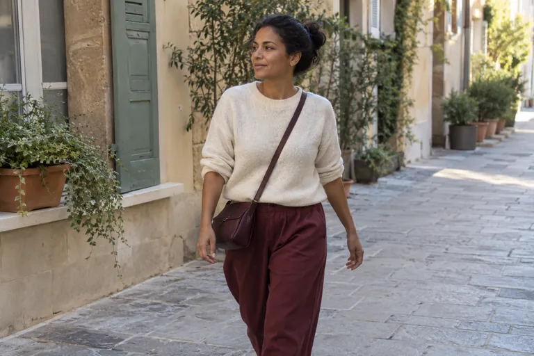 Une femme marche dans une rue piétonne en regardant les alentours.