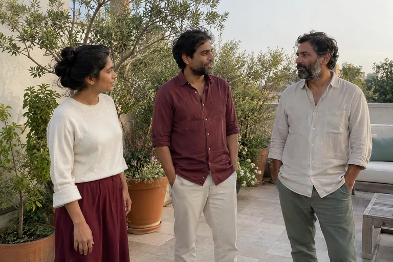 Trois adultes discutent debout sur une terrasse.