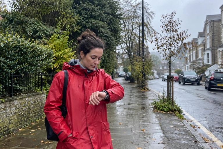 Une femme à l’arrêt sur un trottoir regarde sa montre