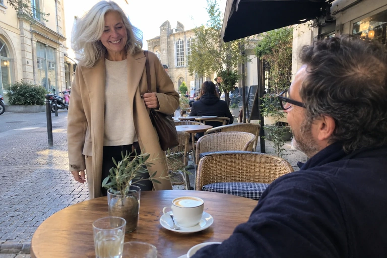 Une femme arrive à une table de café où un ami l’attend