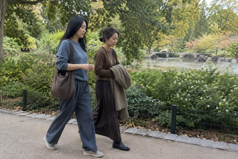 Deux femmes marchent côte à côte sur une allée de parc.