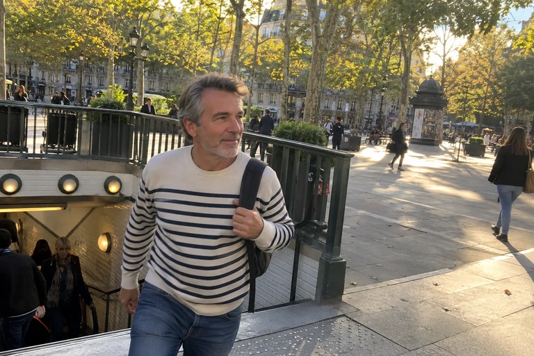 Un homme sort d’une station de métro vers une place arborée