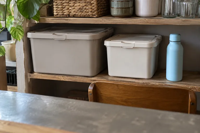 Deux boîtes fermées et une gourde sont rangées sur une étagère.
