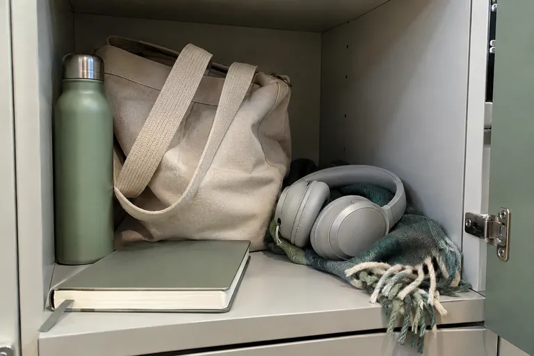 Un sac, une gourde, un casque et un carnet sont rangés dans un casier.