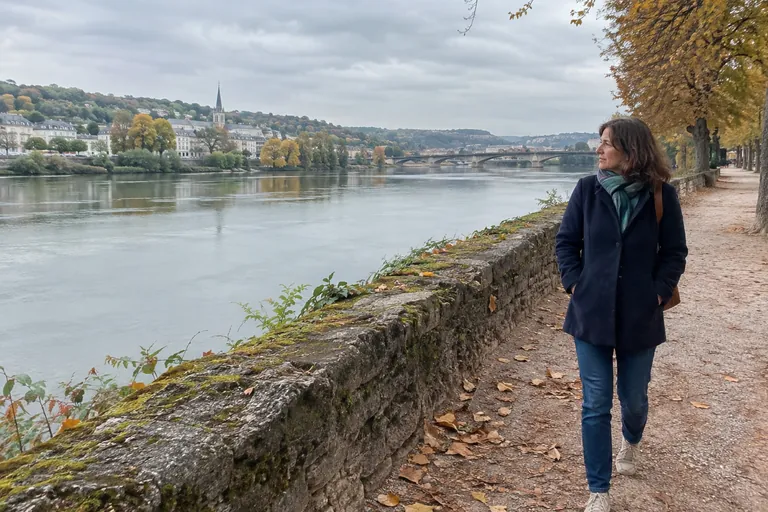 Une femme se promène au bord d’une rivière en automne, absorbée par le paysage
