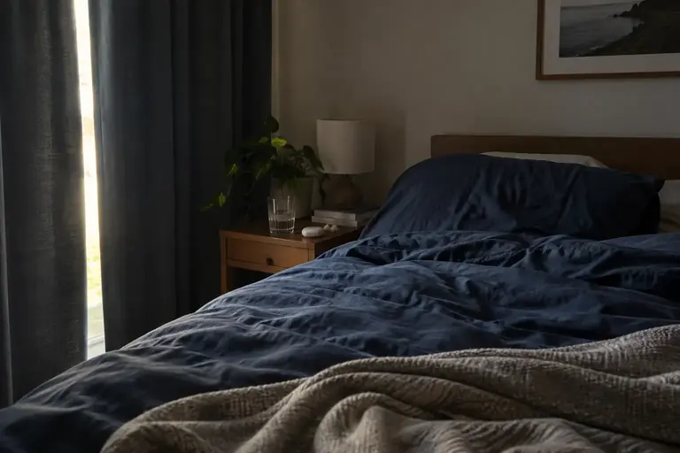Une chambre préparée pour dormir en journée, avec des rideaux épais et une literie sombre, sans horloge lumineuse