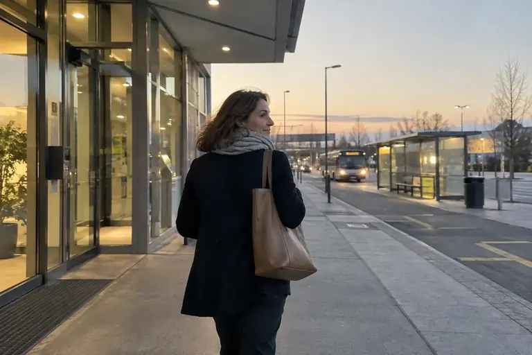 Une femme quitte un bâtiment au petit matin près d’un arrêt de transport