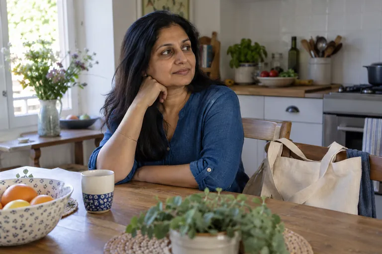 Une femme est assise à une table de cuisine près d’un sac